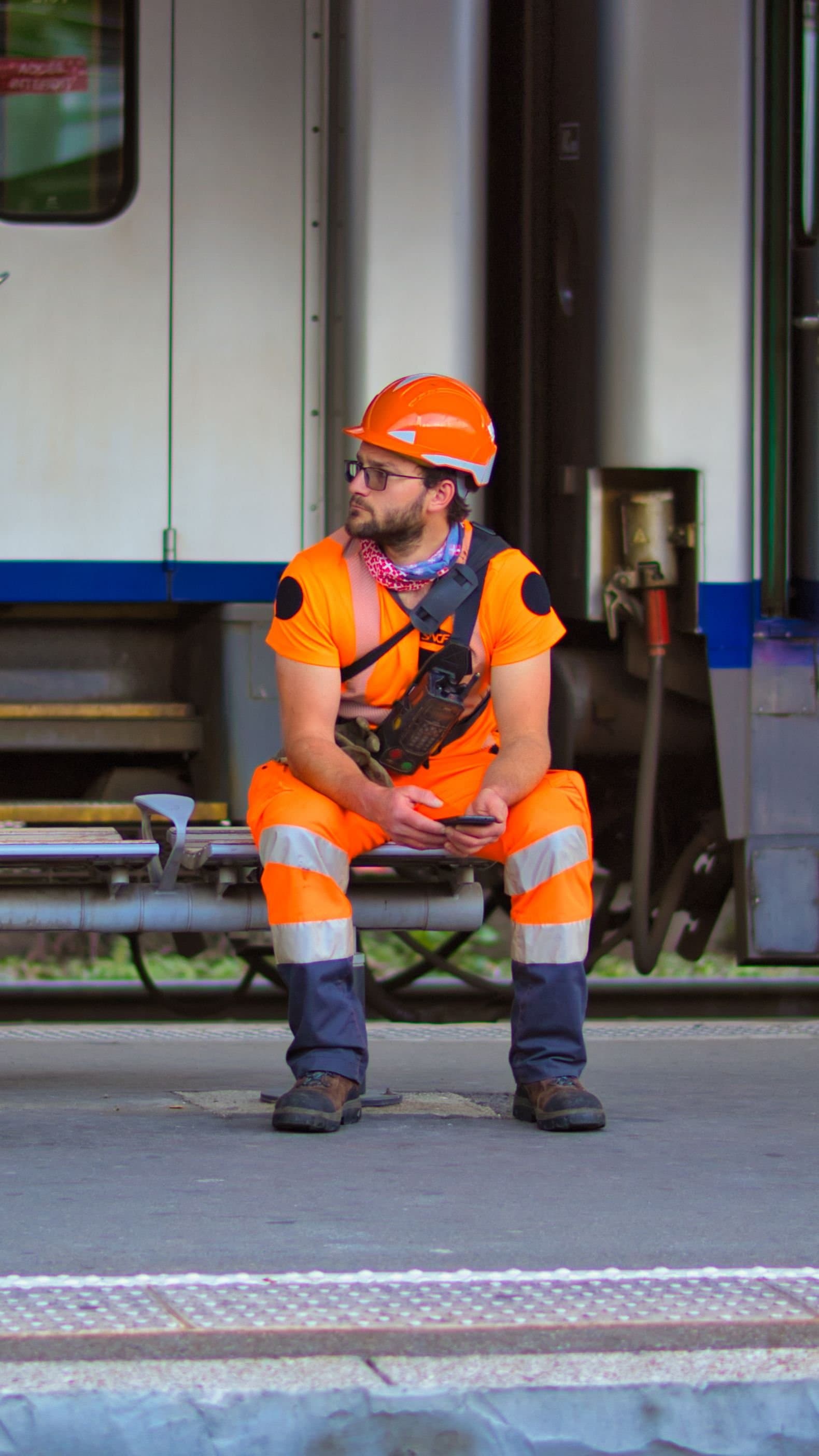 Ouvrier en tenue haute visibilité et casque de chantier consultant son smartphone lors d'une pause